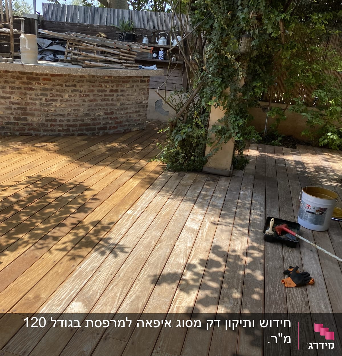 מרפסת עץ עם כלים לצביעת דק וגינה מסביב